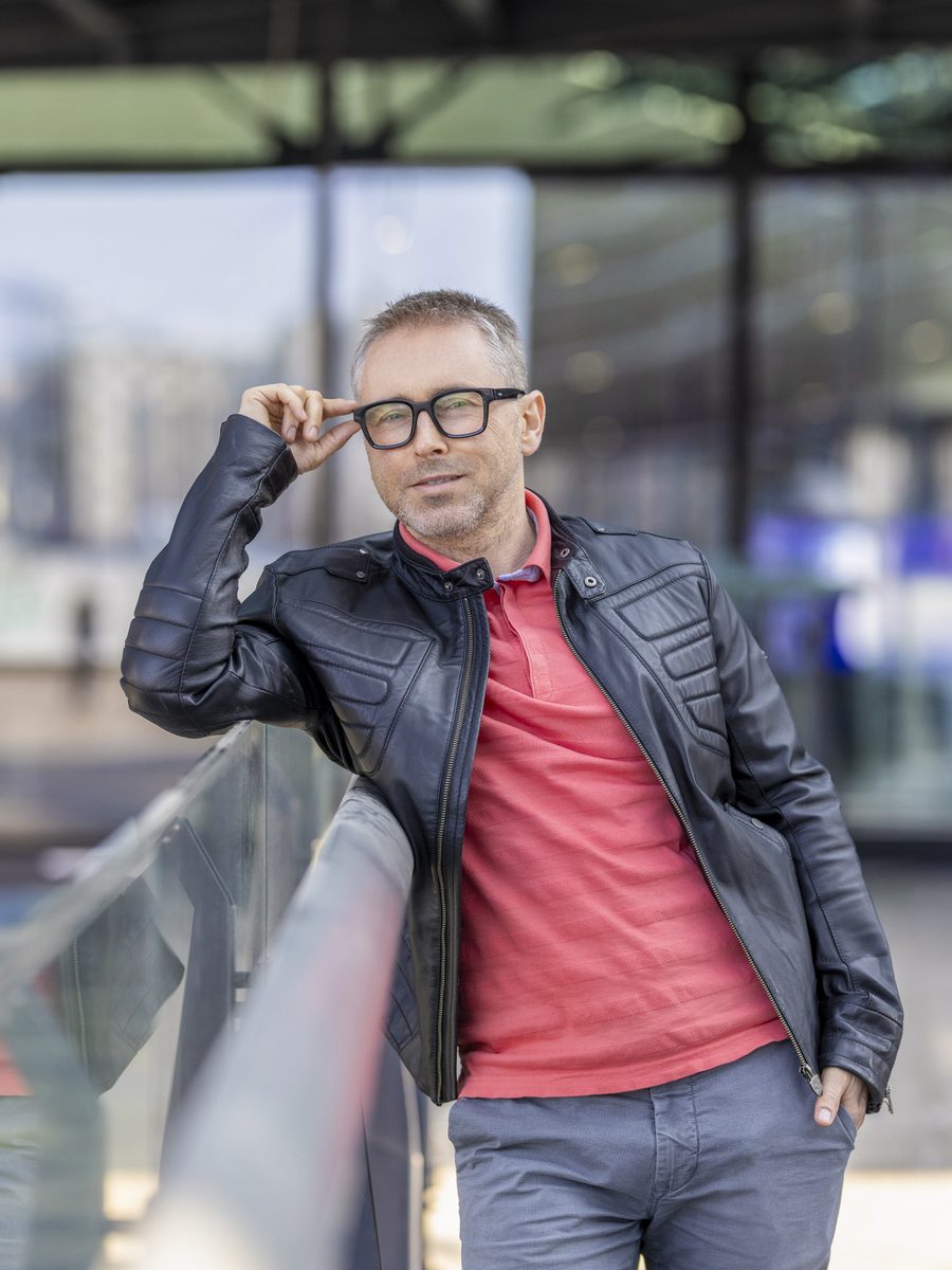Łukasz Socha, autor strony, w skórzanej kurtce, poprawia okulary